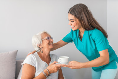 caregiver serving coffee to the elder woman
