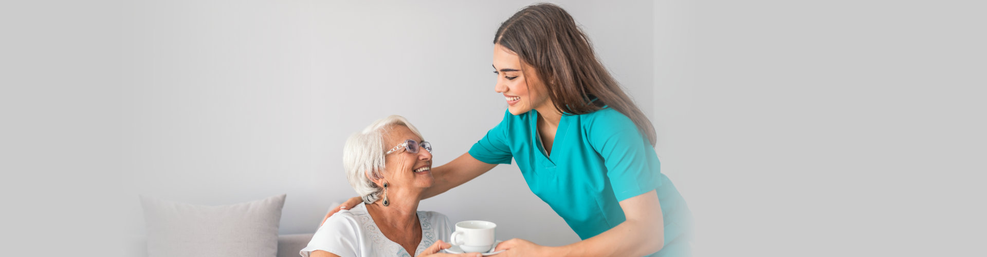 caregiver serving coffee to the elder woman