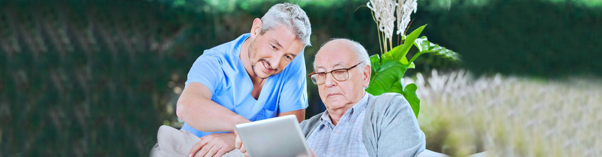 elder man looking at a table with caregiver